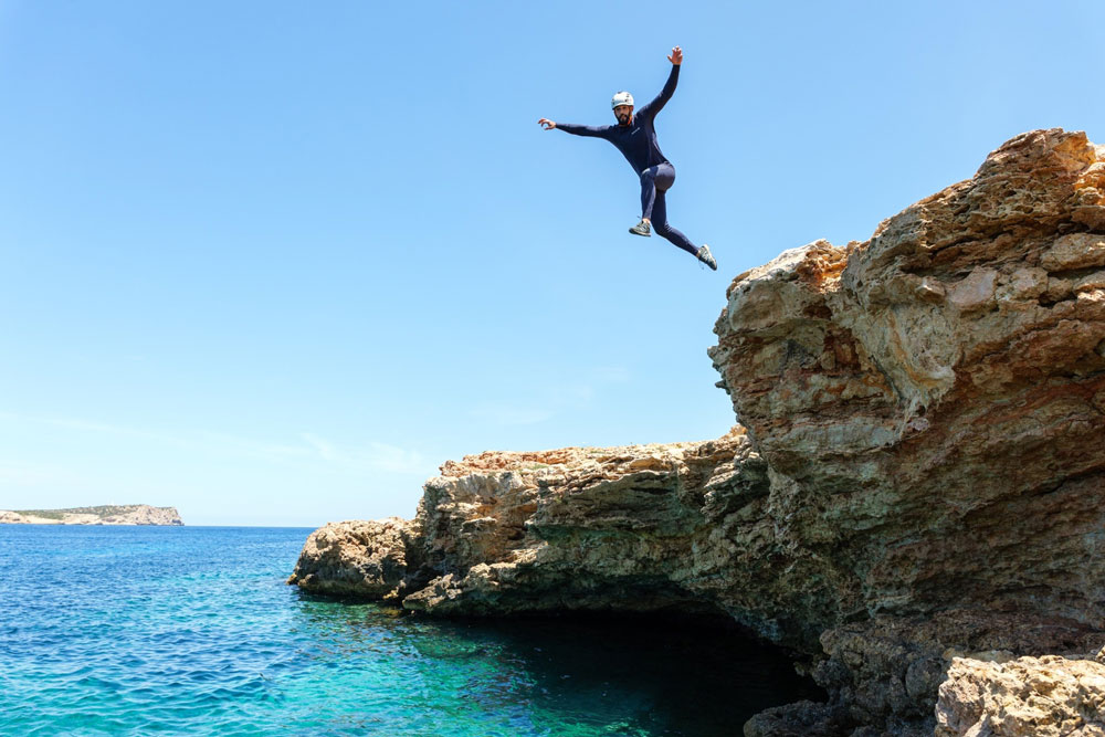 persona saltando al mar durante actividad de coasteering en Sa Punta, Ibiza